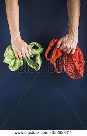 A String Bag In One Man's Hand, In The Other A Plastic Bag On A Dark Blue Background. Side View.