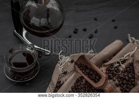 Coffee Style, Cup Of Coffee And Coffee Beans Roating With Old Wooden Scoop And Coffee Beans Around O