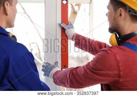 Workers Using Bubble Level For Installing Window Indoors, Closeup