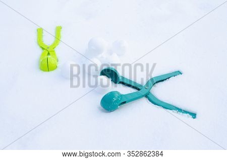 Two Snowball Maker Lying In The Snow, Next To A Slide Of Snowballs Made With Their Help