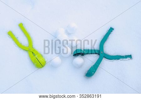 Two Snowball Maker Lying In The Snow, Next To A Slide Of Snowballs Made With Their Help