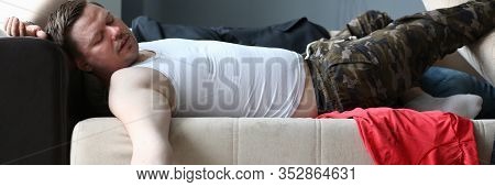 Portrait Of Lying Man Drunkard Lying On Comfortable Sofa And Holding Bottle Of Expensive Alcohol. Be