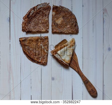 Three Thin Pancakes On White Boards And A Wooden Cooking Spatula With A Pancake
