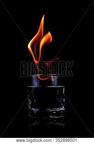 Glass With Vodca And Fire Flame On Black Background