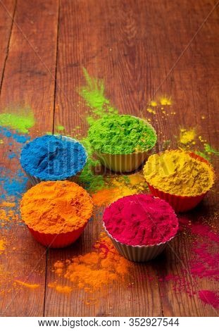 Holi color powder. Organic Gulal colours in bowl for Holi festival, Hindu tradition festive. Blue, pink, magenta, orange, yellow holi dry paints on wood desk background