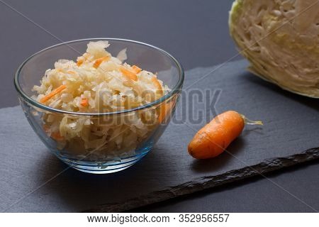 Homemade Fermented Cabbage With Carrot In Glass Bowl And Fresh Head Of Cabbage, Carroy On Black Ston