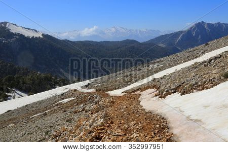 mountain pathway on slope among stomes and snow . Spring in Turkey