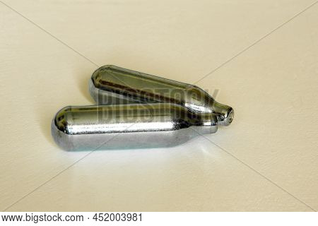 Pair Of Nitrous Oxide Or Laughing Gas Canisters Used In Frothing Cream Or Sniffing Isolated On A Whi