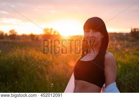 Brunette Woman In White Blouse With Baldric On Summer Field On Sunset. Peaceful Time. Millennial Gen