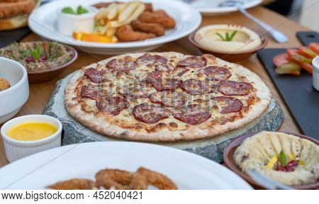 Pepperoni Pizza With Along With Other Arab Cuisine Items On The Table.
