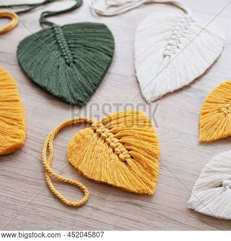 Macrame Leaves In Yellow, Green  And Natural Color On The Wooden Background. Cotton Rope Decor Macra