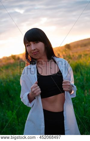 Young Woman In Baldric On The Summer Field On Sunset Or Sunrise. Peaceful Calm Female. Trendy Clothe