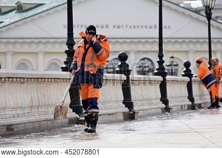 Moscow, Russia - April 2022: Worker With Shovel Talking On Mobile Phone Standing On Manezh Square. S
