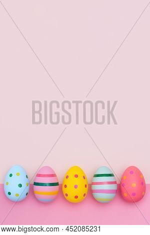Easter Border Of Vivid Easter Eggs On Two-tones Pink Background. Multi-colored Striped And Dotted Eg