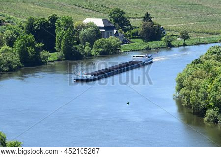 Trittenheim, Germany - 06 01 2021: Cargo Ship In The Blue Mosel With Vineyards On The Shore