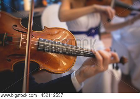 Male Violin Player, Fiddler Violinist With A Bow Performing Music On Stage During Concert With Orche