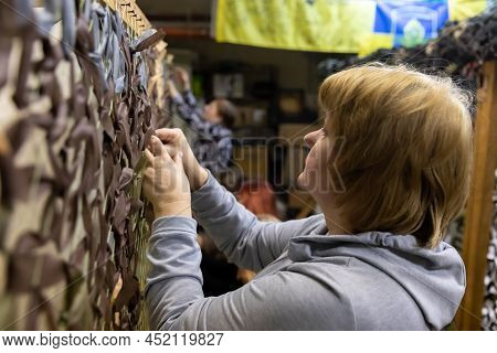 Kyiv, Ukraine - Apr. 01, 2022: A Group Of Volunteers In A Shelter Making Camouflage Net, From Differ