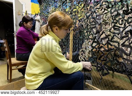 Kyiv, Ukraine - Apr. 01, 2022: A Group Of Volunteers In A Shelter Making Camouflage Net, From Differ