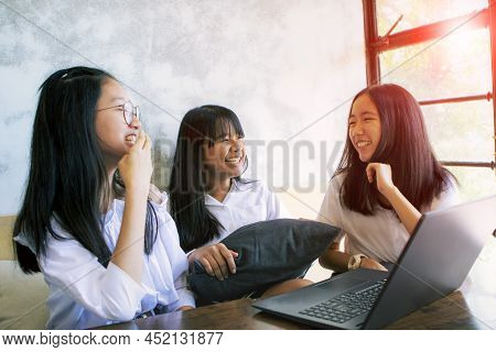 Three Asian Teenager Laughing With Happiness Face While Working On Aptop In Living Room