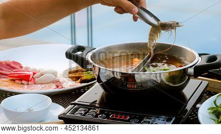Man Hand Take River Prawn And Put It In Boiling Pot Shabu Shabu Hotpot Style In Japanese Restaurant.