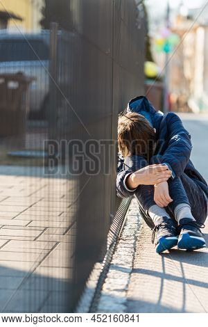 Sad Boy Sitting And Crying On Street. Negative Emotion.