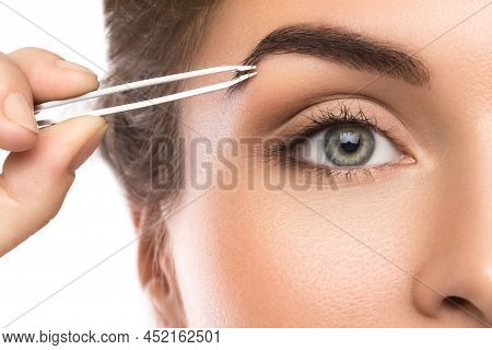 Close-up Of Female Face And Eyebrow With Tweezers