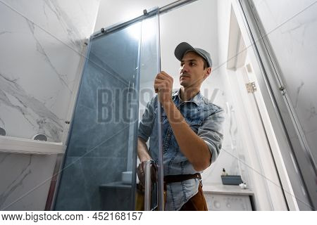 Workers Are Installing Glass Door Of The Shower Enclosure.