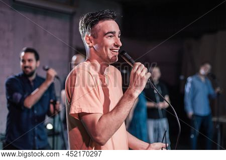 Smiling And Witty Stand Up Actor Comedian On Stage, Talking And Singing