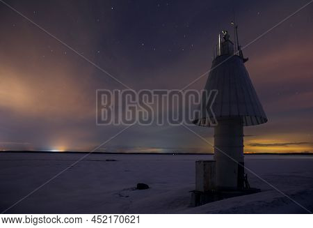 Night Winter Landscape. A Starry Multi-colored Sky Over A Frozen Bay And A Mushroom-shaped Navigatio