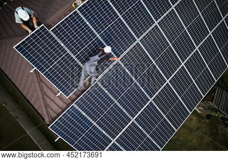 Man Technician Mounting Photovoltaic Solar Moduls On Roof Of House. Mounter In Helmet Installing Sol