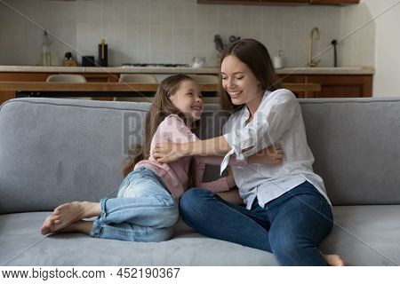Happy Playful Mom Tickling Excited Daughter Girl On Sofa