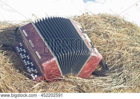 The Russian Musical Traditional Instrument Bayan Lies On The Hay On The Maslenitsa Holiday.
