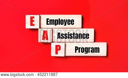 On A Bright Red Background, Wooden Cubes And Blocks With The Text Eap Employee Assistance Program. M