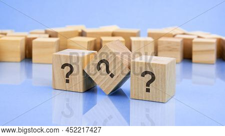 Three Wooden Cubes With The Question Marks On On The Bright Surface Of A Pale Lilac Table. The Inscr
