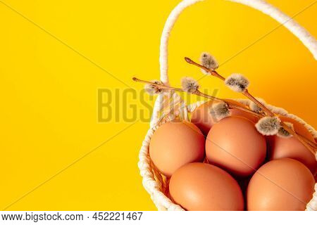 Easter Holiday Card With Basket Full Of Eggs On Yellow Background Decorated With A Pussy Willow Twig