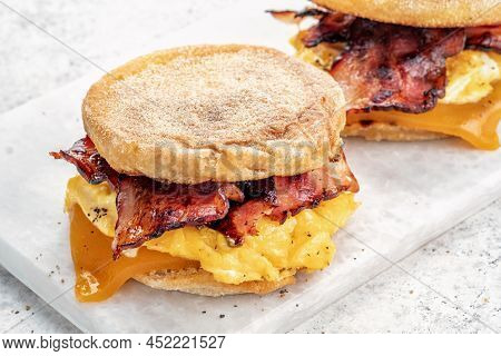 English Muffin, Scrumbled Egg, Ham, And Cheese Breakfast Sandwich On A Cutting Board