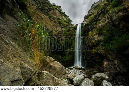 Waterfall Over The White Rocks And Green Undergrowth