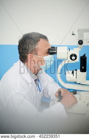 Ophthalmologist In Protective Mask Examined Eyes Of Patient With Modern Autorefractometer