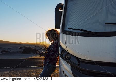 People On Travel With Modern Camper. Woman Using Mobile Phone Roaming Against Big Motorhome. Concept