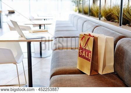 Background Image Of Paper Shopping Bags With Red Sale Sign On Seat In Empty Food Court At Shopping M