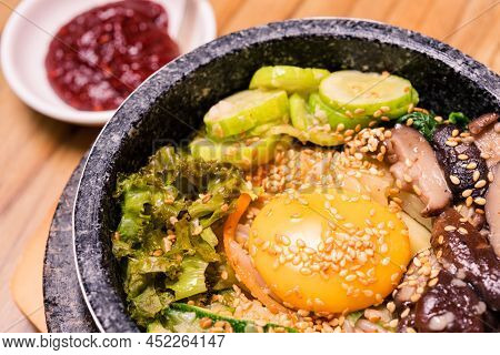 Bibimbap In A Black Heated Stone Bowl, Korean Traditional Dish- Bibimbap Mixed Rice With Vegetables 