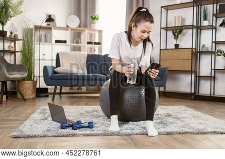 Happy Fitness Woman Training On Swiss Ball In Living Room. Portrait Of Muscular Woman Enjoying Home 