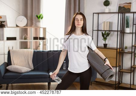 Woman Drinking Water At The Home. Muscular Woman Taking Break After Exercise. Smiling Attractive Fit