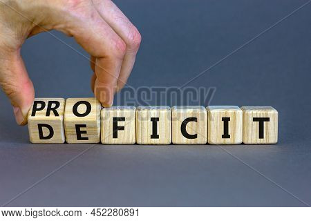 Proficit Or Deficit Symbol. Businessman Turns Cubes, Changes The Word Deficit To Proficit. Beautiful