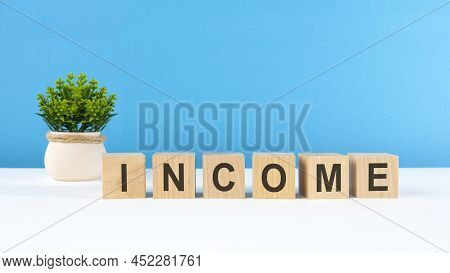 The Word Income Is Written On Wooden Cubes On A Light Blue Background