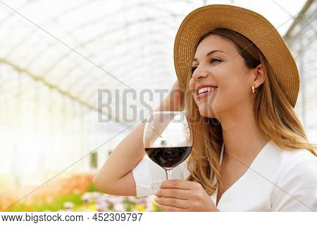 Close-up Of Smiling Woman With Straw Hat Holding A Glass Of Red Wine