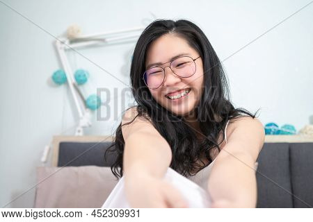 Asian Young Glasses Woman Stretches Oneself On Her Bed In The Morning.