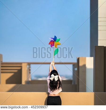 Asian Woman Posts And Play Windmill Toy Colourful Rainbow Colour On The Building Rooftop In Sunset T