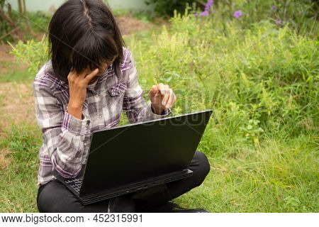 Farmer Stressed And Use Computer Laptop In Parks. She Sad Because The Business Is Losing. Technology