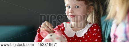 Portrait Of Cute Little Child Putting Coin Into Piggy Bank. Mother Teach Daughter To Save Up, Save T
